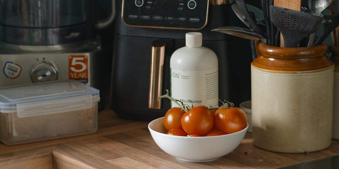 Air fryer and other small kitchen appliances beside tomatoes on a kitchen counter