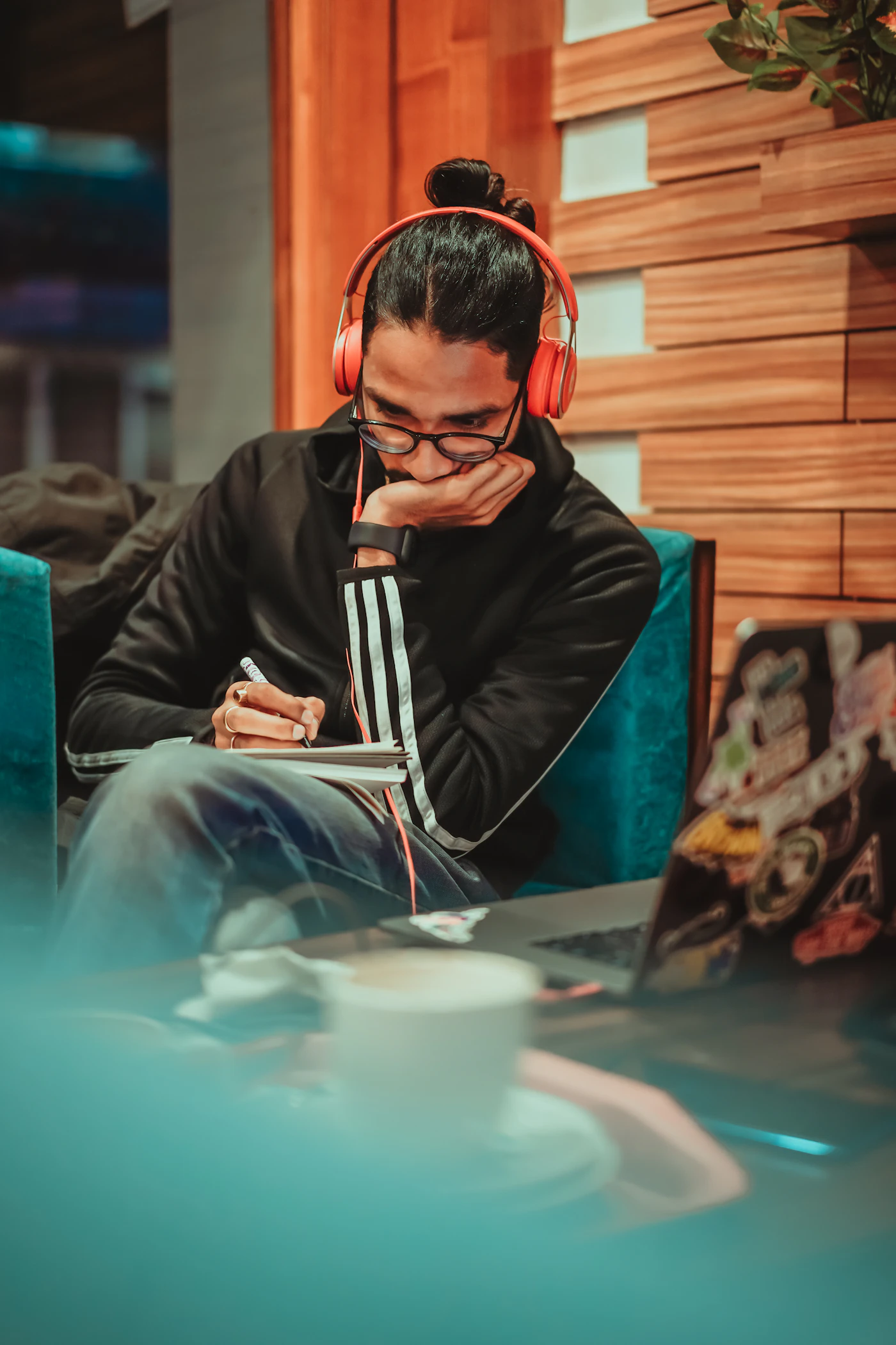 A person wearing headphones while writing in a notebook